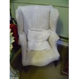 A GEORGIAN DESIGN WING BACK ARMCHAIR having ivory damask effect all over upholstery with extra