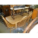 AN ERCOL DINING SUITE comprising rectangular topped table on four plain slayed legs, together with a