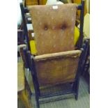 AN EBONISED FRAMED FOLDING STEAMER ARMCHAIR with remains of period upholstery