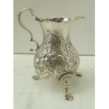 SAMUEL MERITON I A GEORGE II SILVER CREAM JUG, fitted 'C' scroll handle, embossed floral and bird