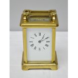 A 20TH CENTURY BRASS FRAMED CARRIAGE CLOCK fitted bevelled glass panels, the white enamel dial
