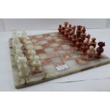 A MEXICAN COLOURED ONYX CHESS BOARD with set of 32 pieces, pawns 5cm high