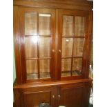 A MODERN MAHOGANY FINISHED BOOKCASE/DISPLAY STAND with twin bar glazed upper doors on a base unit