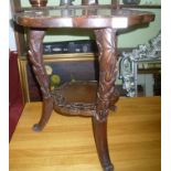 AN EASTERN CARVED WOOD TWO TIER OCCASIONAL TABLE on three outswept legs