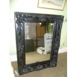 A LARGE RECTANGULAR BEVEL PLATE WALL MIRROR in fancy moulded black finished frame
