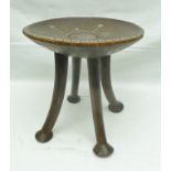 AN AFRICAN CARVED WOOD DISH TOP STOOL on four supports with splayed feet, the top inlaid white