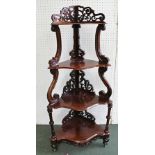 A VICTORIAN ROSEWOOD CORNER WHATNOT, pierced and carved decoration, four serpentine fronted tiers,