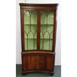 A GEORGIAN DESIGN MAHOGANY BOW FRONT FULLSTANDING CORNER CUPBOARD, having dentil cornice, with