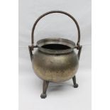 AN EARLY BRONZE CAULDRON, raised on three cast supports, with iron swing handle, top rim 21cm