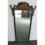 AN EBONISED FRAMED WALL MIRROR with fret cut crest, having chinoiserie decoration, plate size 75cm x