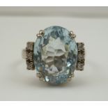 AN AQUAMARINE AND DIAMOND RING, the oval facet cut central stone flanked by a row of three