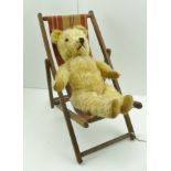 A MID 20TH CENTURY GOLDEN PLUSH TEDDY BEAR, 36cm high, on a folding deck chair