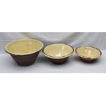 A GRADUATED SET OF THREE VINTAGE TERRACOTTA DAIRY BOWLS with inner cream glaze, 35cm, 42cm and