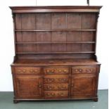 A GEORGIAN OAK DRESSER WITH PLATE RACK, the base fitted drawers and cupboards with brass handles,