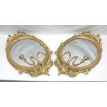 A PAIR OF 19TH CENTURY GILT GESSO OVAL FRAMED WALL MIRRORS with Mer-Putti crests and twin candle
