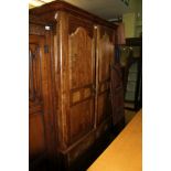 A MIXED WOOD TWO DOOR WARDROBE with insert marble panels, having full width hanging rail on a base