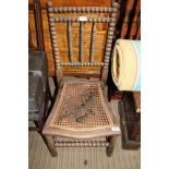 AN EARLY 20TH CENTURY BOBBIN TURNED BERGERE SEATED SINGLE CHAIR