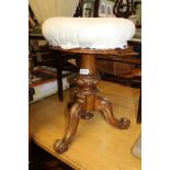 A VICTORIAN CARVED WALNUT BASED ADJUSTABLE CIRCULAR PAD TOP MUSIC STOOL