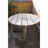 A LARGE TEAK PLANK TOPPED CIRCULAR GARDEN TABLE with umbrella aperture