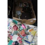 A BOX CONTAINING CASED BINOCULARS, A PATCHWORK QUILTED THROW, enamel backed dressing table items and