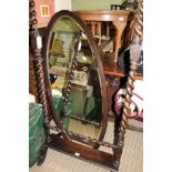 AN OAK FRAMED OVAL BEVELLED PLATE ROBING MIRROR, on barley twist and block uprights, with candle