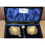A CASED PAIR OF CHESTER HALLMARKED SILVER SCALLOP SHELL SALTS with matching spoons, dating from 1904