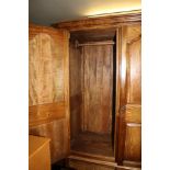 A MIXED WOOD TWO DOOR WARDROBE with insert marble panels, having full width hanging rail on a base