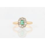 An emerald and diamond cluster ring, set with a central emerald cut emerald, measuring approx.