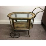 A brass and mahogany vitrine tea cart with spoke wheels and brass pierced gallery to top.