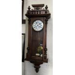 A walnut and glass cased wall clock with swinging pendulum.