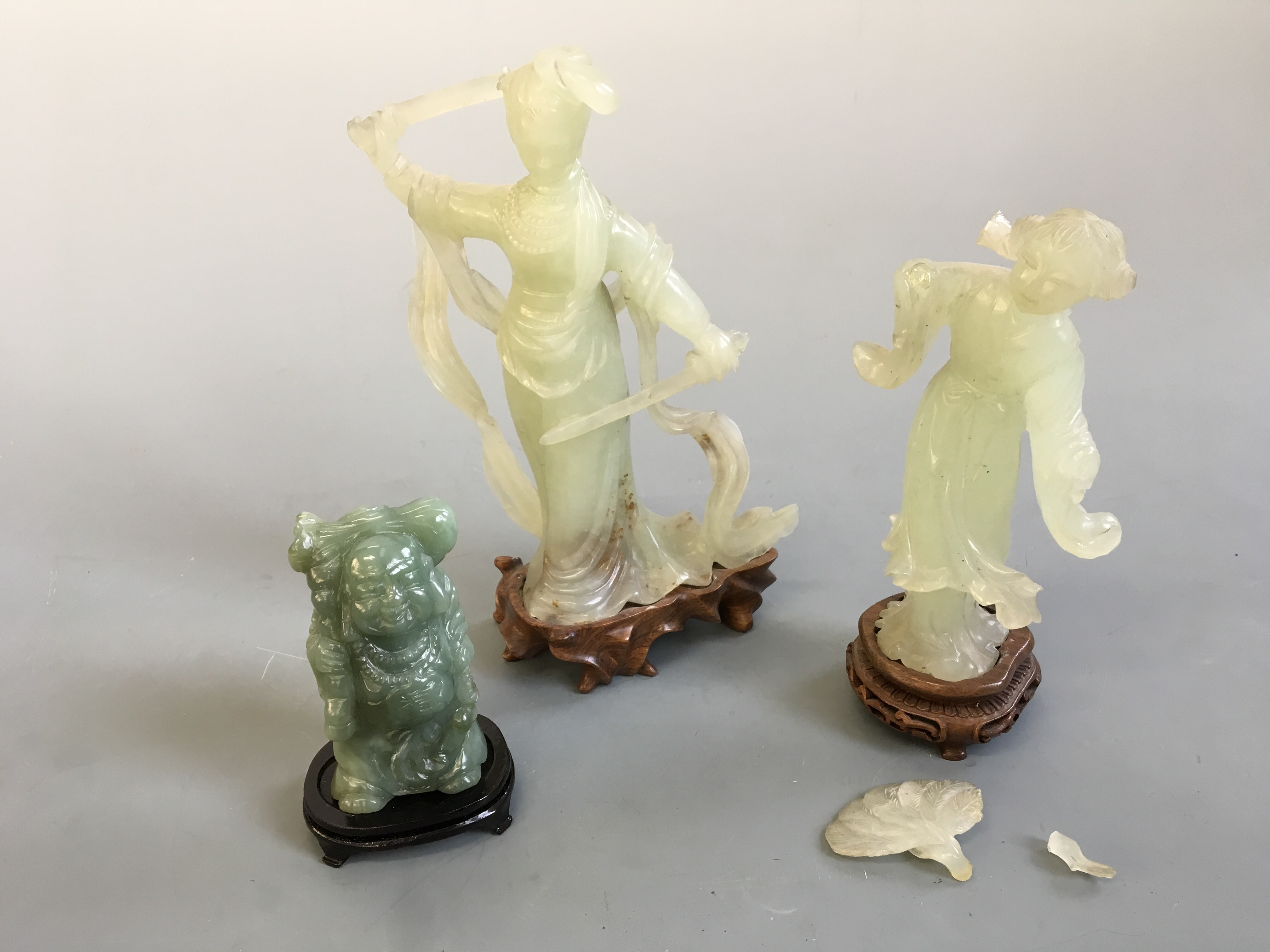 Three jade figurines on wooden bases, depicting buddha, female warrior and female with fan. (One