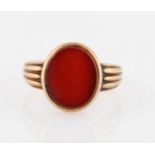 A 9ct yellow gold gents signet ring, set with an oval cut orange hardstone, hallmark partially