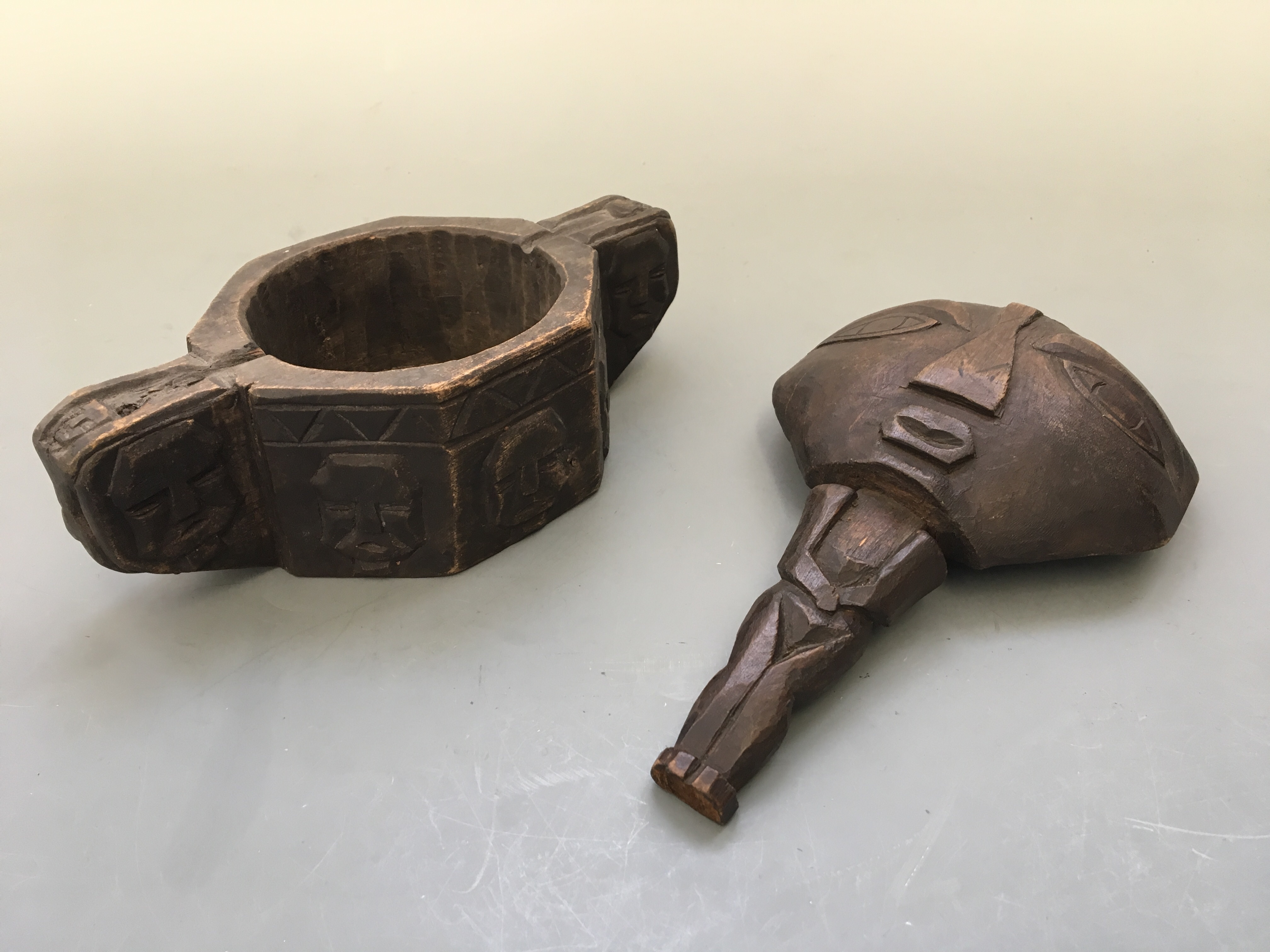 An aboriginal loving cup carved with face and zig zag design to rim, with a wooden spoon carved in