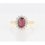 An 18ct yellow gold garnet and diamond cluster ring, set with a central oval cut garnet surrounded