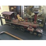 A wooden red painted model steam locomotive with small teddy bear.
