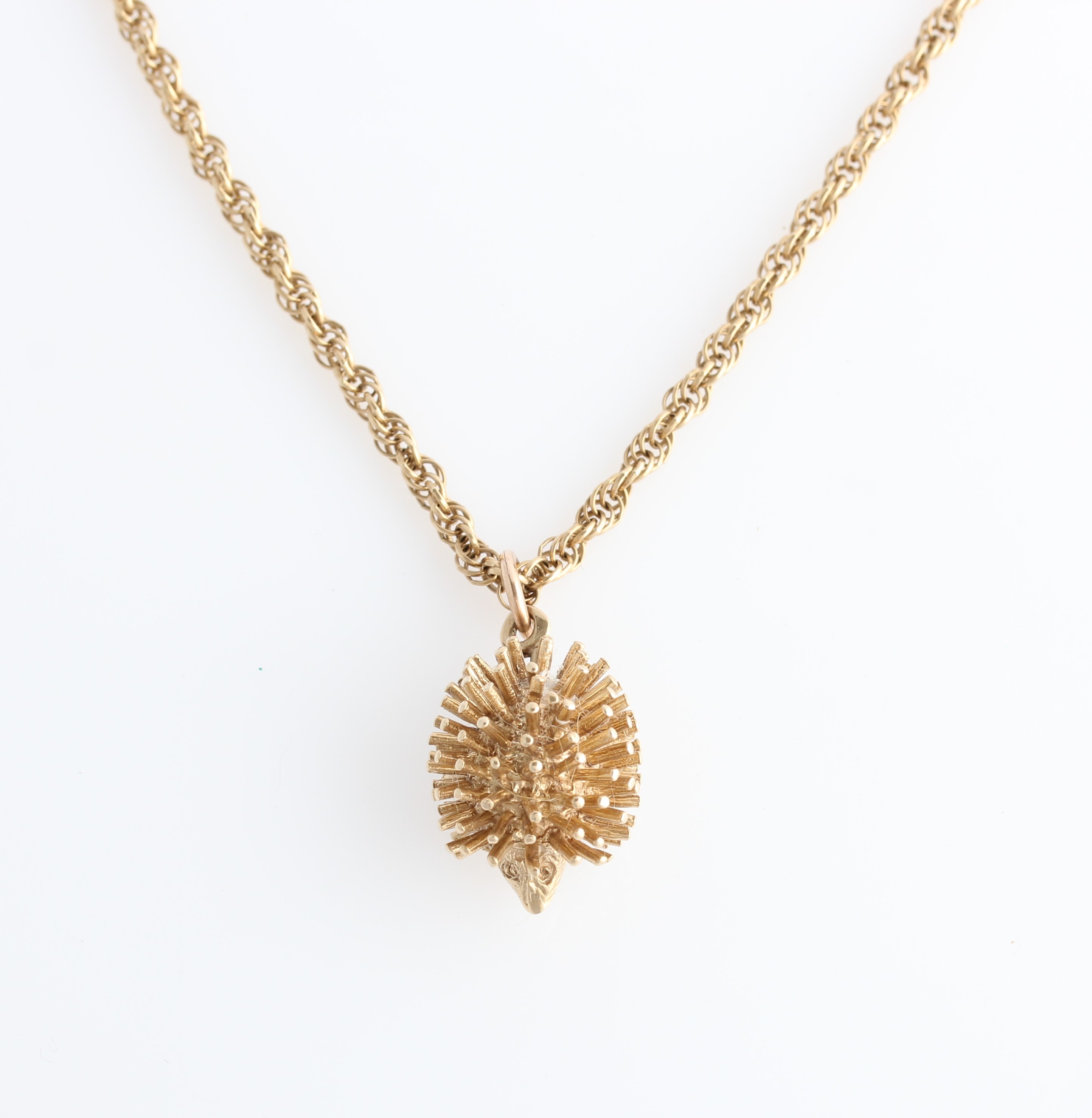 A hallmarked 9ct yellow gold hedgehog pendant, on a fancy curb link chain, stamped 9ct.