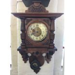 A walnut wall clock with swinging pendulum.