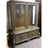 A Dutch oak cabinet with two doors to base and two glazed doors to top, on claw feet.