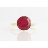 A hallmarked 9ct yellow gold treated ruby single stone ring, set with a round cut glass filled ruby,