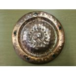 An arts and craft style hand beaten copper round plate with female profile to centre.