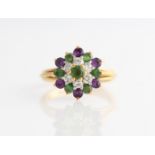 An 18ct yellow gold emerald, amethyst and diamond cluster ring, set with round cut amethysts,
