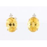 A pair of heliodor and diamond stud earrings, each set with an oval cut heliodor, measuring