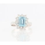 An aquamarine and diamond cluster ring, set with an emerald cut aquamarine, measuring approx. 8x6mm,