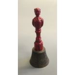 A Chinese hand held bell with red painted figure of man to handle.