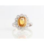 An 18ct white gold yellow / orange sapphire and diamond cluster ring, set with an oval cut