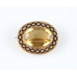 A citrine and enamel brooch, set with an oval cut citrine, measuring approx. 26x19mm, surrounded