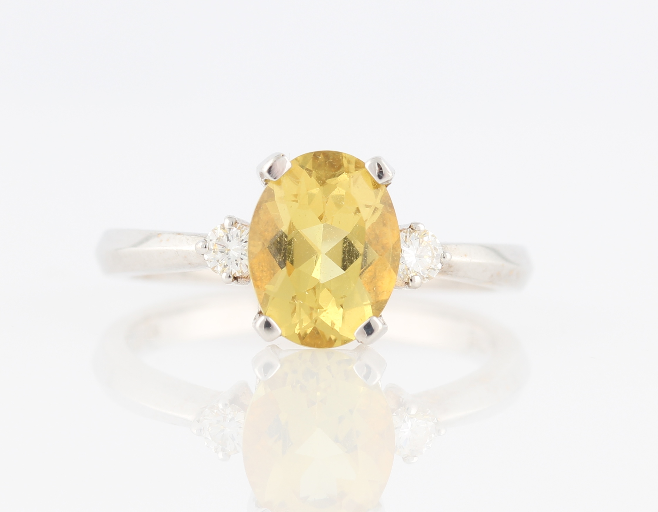 A heliodor and diamond three stone ring, set with a central oval cut heliodor, measuring approx.