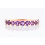 *An amethyst half eternity ring, set with eleven round cut amethysts, rose metal stamped 375/1000,