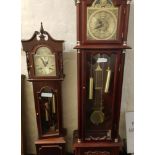 Two modern long cased clocks with brass faces and Roman numerals.