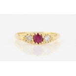 An 18ct yellow gold ruby and diamond three stone ring, set with a central round cut ruby,